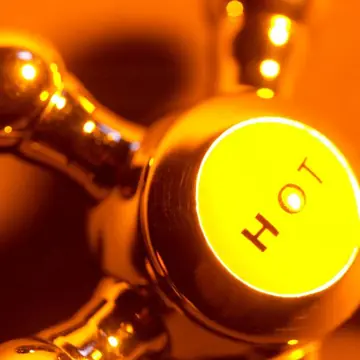 Registro com etiqueta HOT iluminado em laranja em instalação de encanamento de água quente