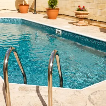 Piscina azul com escada inox e água limpa mantida pela hidráulica de filtragem